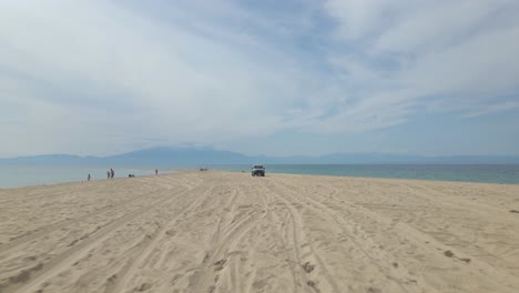 4k-moving-backwards-close-to-the-ground-clip-over-a-peninsula-on-the-tropical-beach-of-Epanomi,-Halkidiki,-Greece