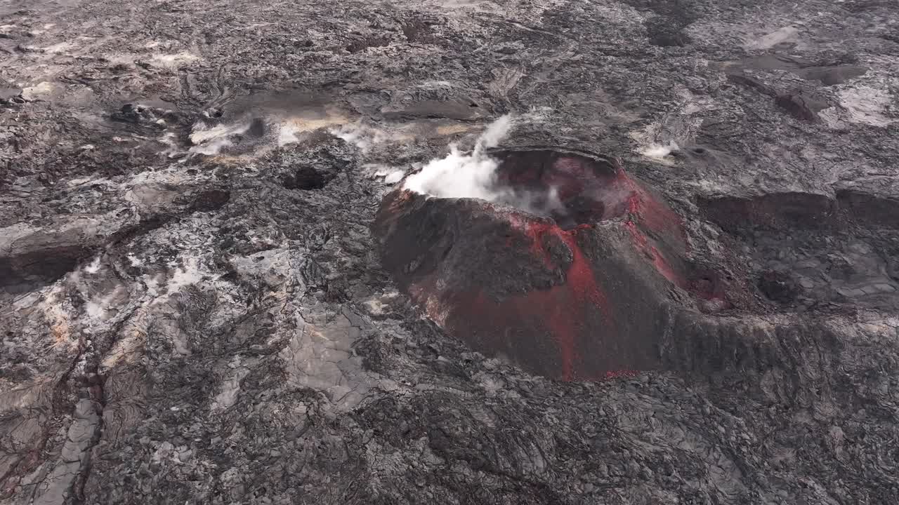 Aerial view of an active volcanic crater with smoke and red lava in Iceland.