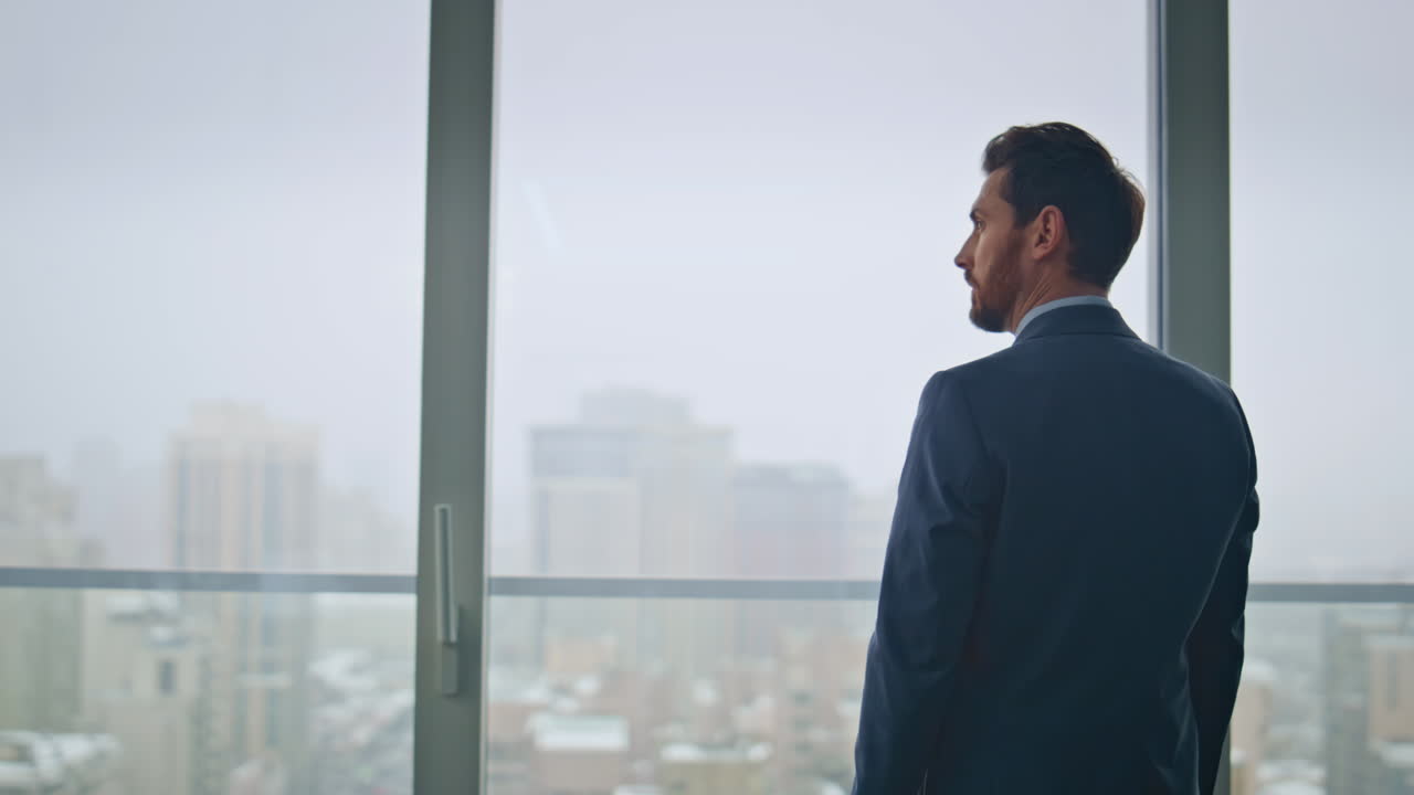 jefe pensativo descansando en la oficina contemplando la ciudad sombría vista de atrás. hombre pensando