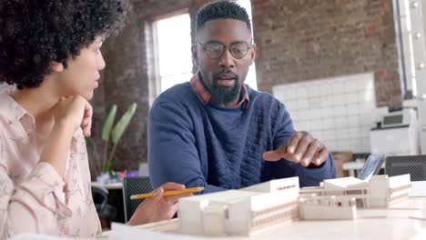 Focused-diverse-architect-colleagues-discussing-work-with-building-model-in-office-in-slow-motion