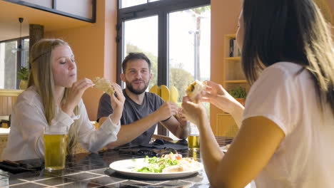 close up view of group of friends talking and eating pizza at restaurant table 1