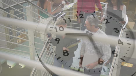 animation of ticking clock against diverse man and woman discussing on stairs at office