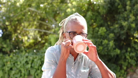 a senior african american woman with braided hair is drinking from mug
