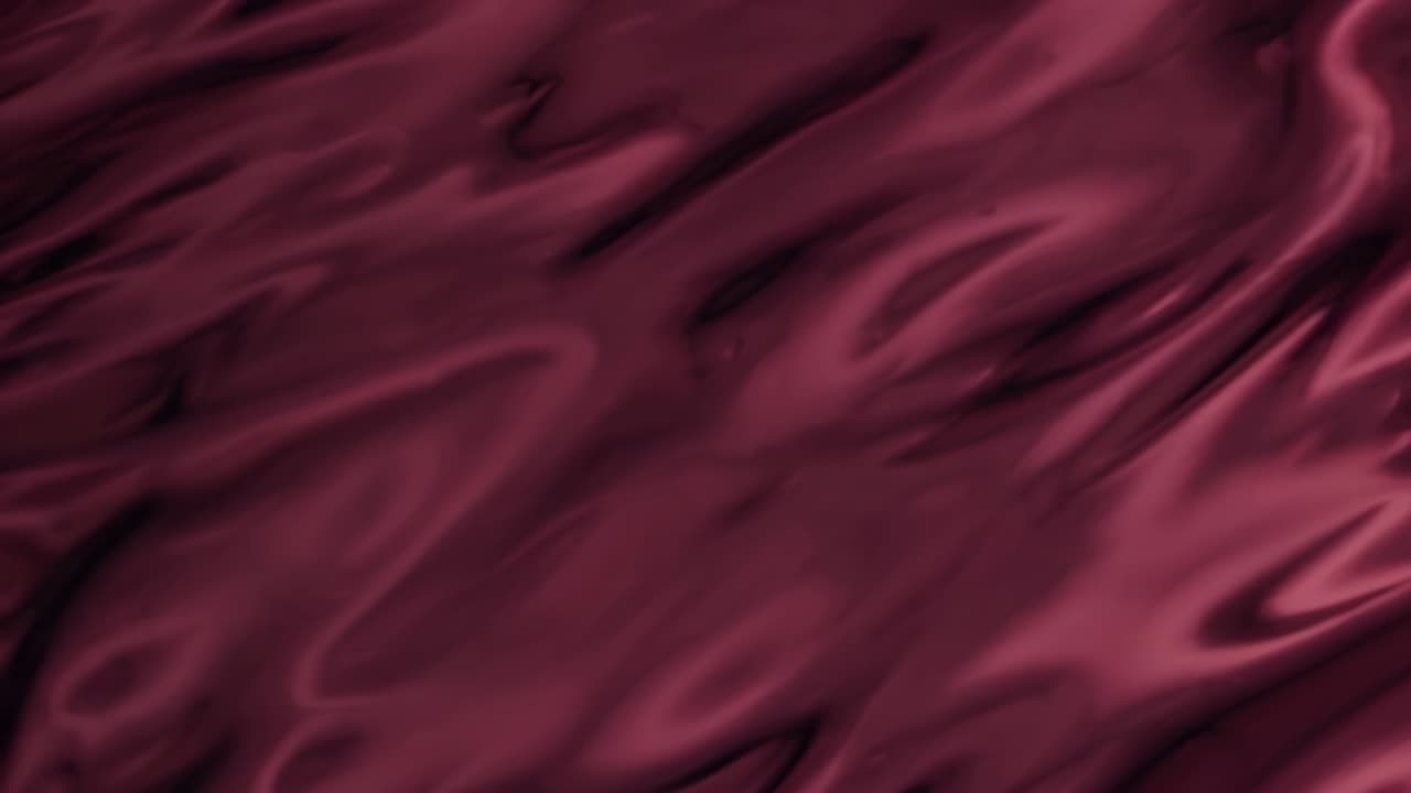 Abstract video background with a silky, maroon texture. The top-down angle captures smooth