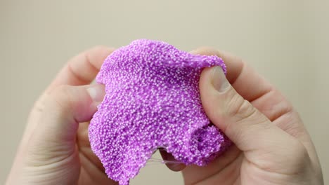 closeup of hands manipulating purple floam slime with small white beads, creating asmr effects for sensory relaxation and stress relief, highlighting the soft, textured, and squishy properties.