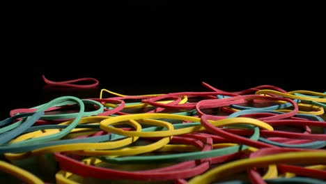 multicolored rubber bands falling on black surface. products for all occasions. zoom in.