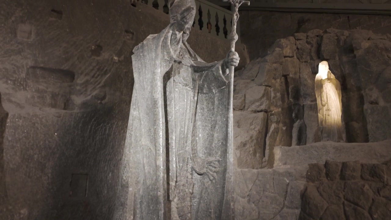 Statua storica di sale nella Miniera di Sale di Wieliczka con dettagli scolpiti nella pietra e omaggio floreale in Polonia