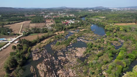 Aerial-shot-over-a-river-with-trees,-houses-and-road-on-both-sides