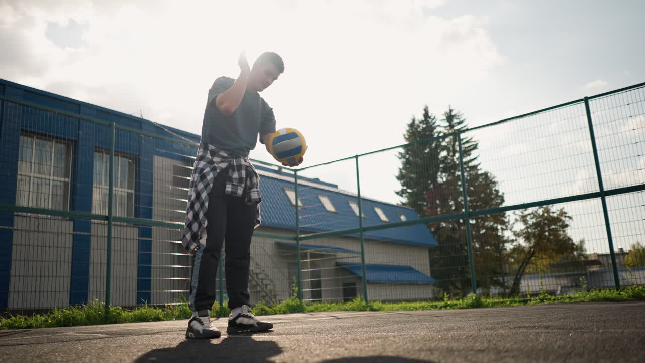 joven saltando voleibol al aire libre, con árboles y arena deportiva en el fondo, preparándose para un juego, demostrando atletismo y enfoque mientras se divierte bajo cielos brillantes