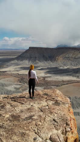 woman overlooking a vast desert canyon landscape from a cliff edge