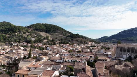 Disparo-Ascendente-De-Un-Dron-Que-Muestra-La-Antigua-Ciudad-De-Esporles-Con-Montañas-Verdes-En-El-Fondo-En-Verano---Mallorca,-España