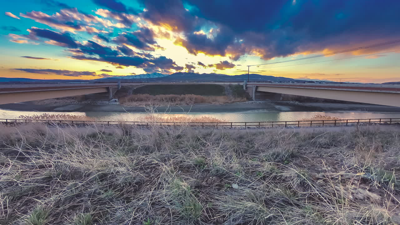 lapso de tiempo entre el tráfico de la carretera con montañas y un colorido atardecer o amanecer en el fondo