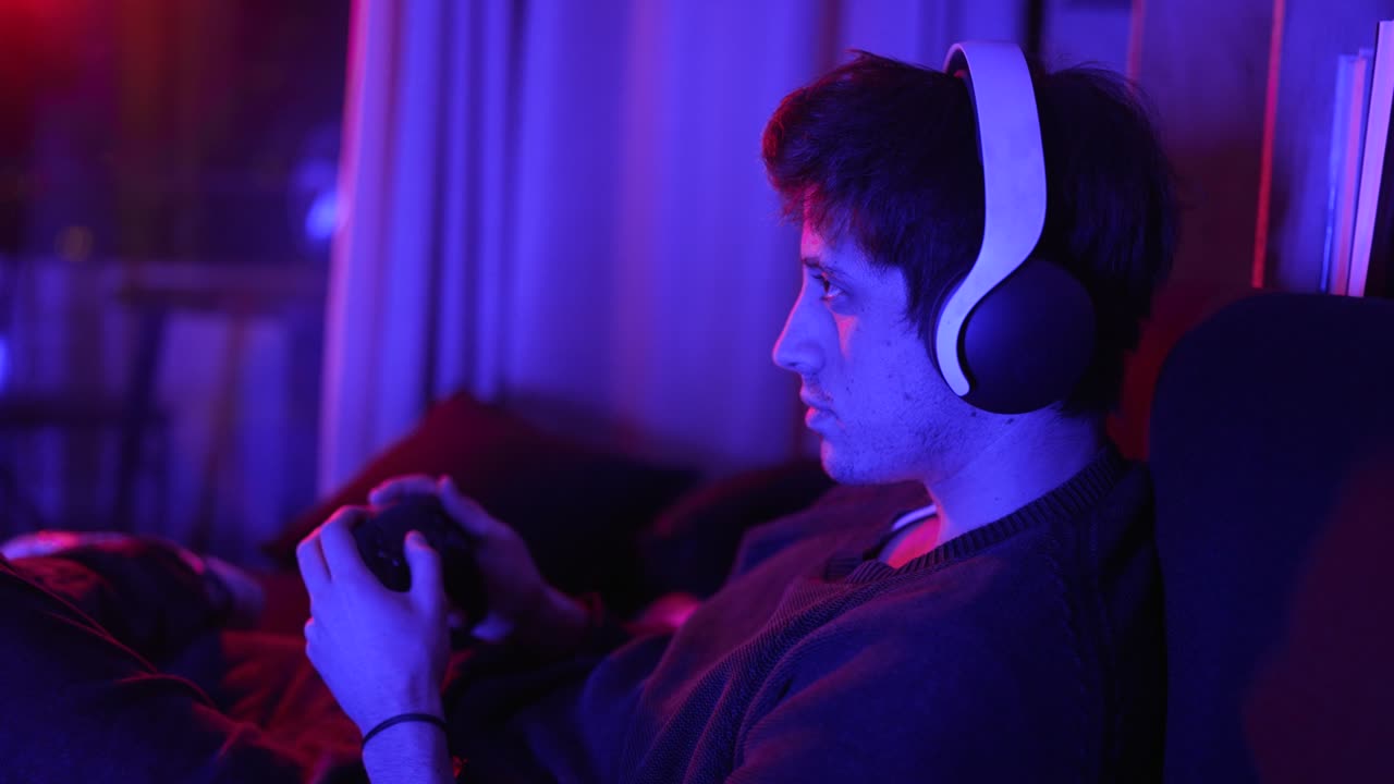 a concentrated man playing video games with headphones looking at the tv screen