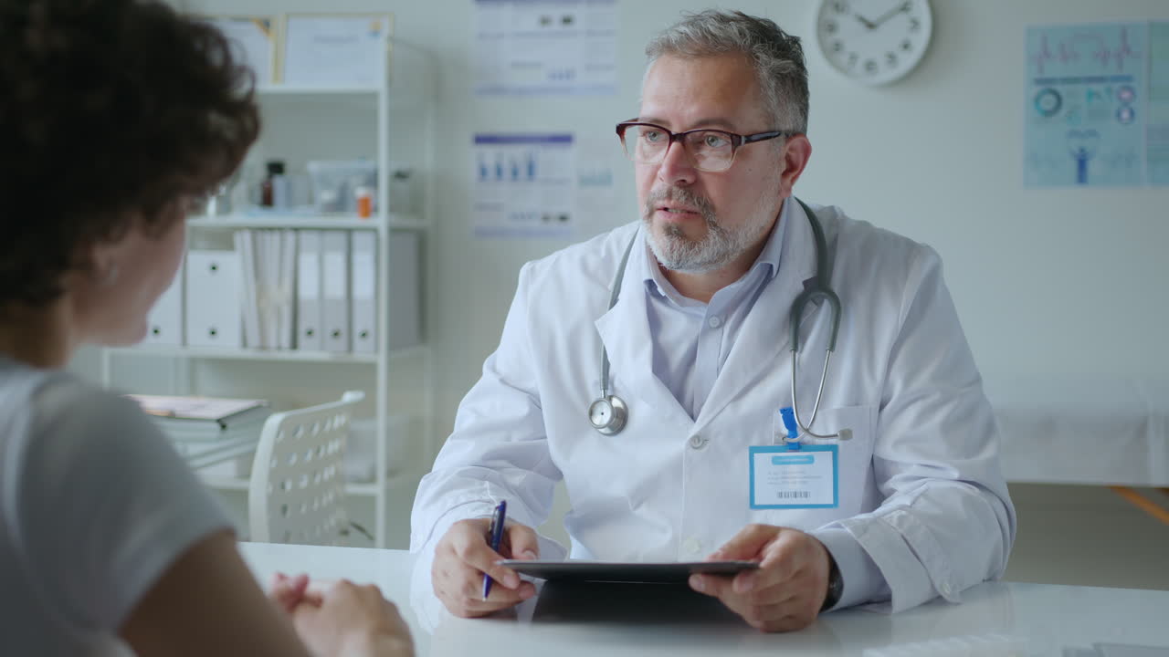 Medico che chiede a un paziente quali sono i sintomi e prende appunti durante la consultazione
