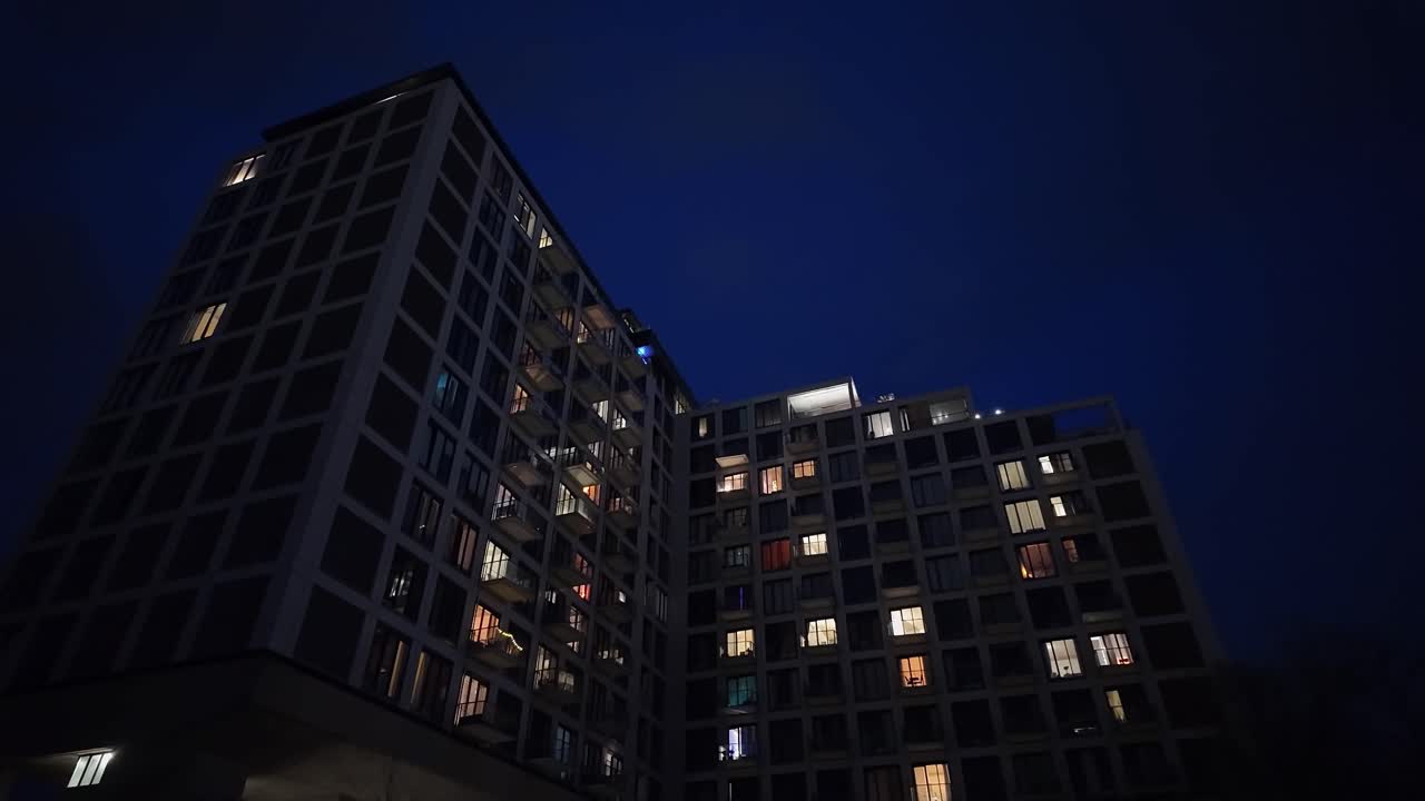 pov de un bloque de apartamentos residenciales por la noche, toma amplia de bajo ángulo en el crepúsculo.