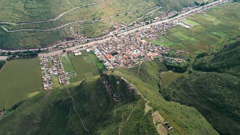 Die-Luftaufnahme-Enthüllt-Die-Schönheit-Der-Ruinen-Des-Pisac-Tals-Mit-Dem-Charme-Des-Dorfes-Und-Der-Üppigkeit-Der-Grünen-Jahreszeit