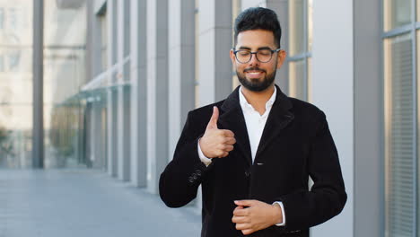 hombre de negocios feliz mostrando pulgares hacia arriba, como señal positiva buena retroalimentación positiva en la calle de la ciudad