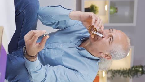 Vertical-video-of-Thoughtful-old-man-with-wedding-ring-in-hand-drinking-alcohol.