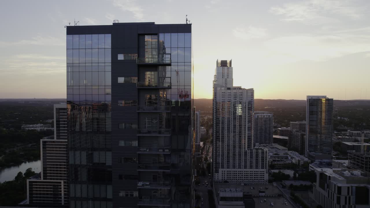 vista aérea pasando un edificio de oficinas reflectante en austin, durante la puesta de sol - seguimiento, disparo de drones