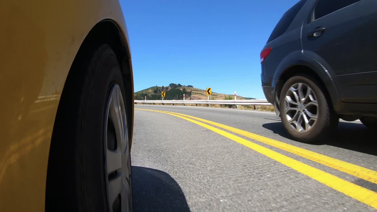 Car front wheel as traveling on mountain road with blue sky and traffic.