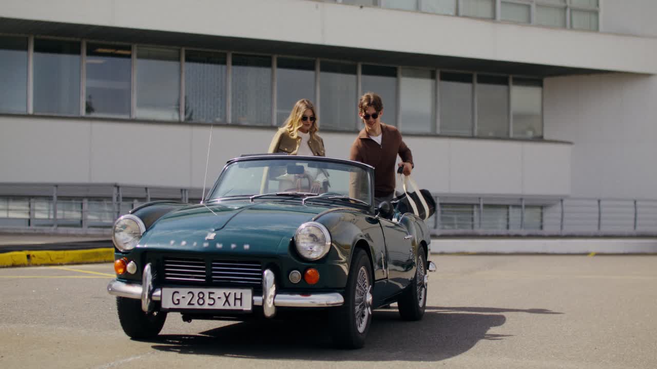 Couple working on vintage convertible car
