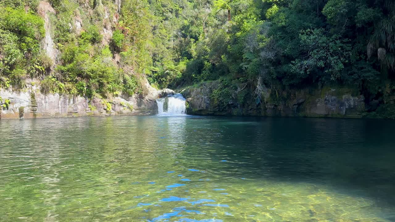 A still video capturing the tranquil Raparapahoe Waterfall in New Zealand’s North Island. The water cascades gently down mossy rocks surrounded by lush green forest and natural beauty