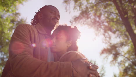 portrait father hug daughter closing eyes in golden sunlight. dad love support.