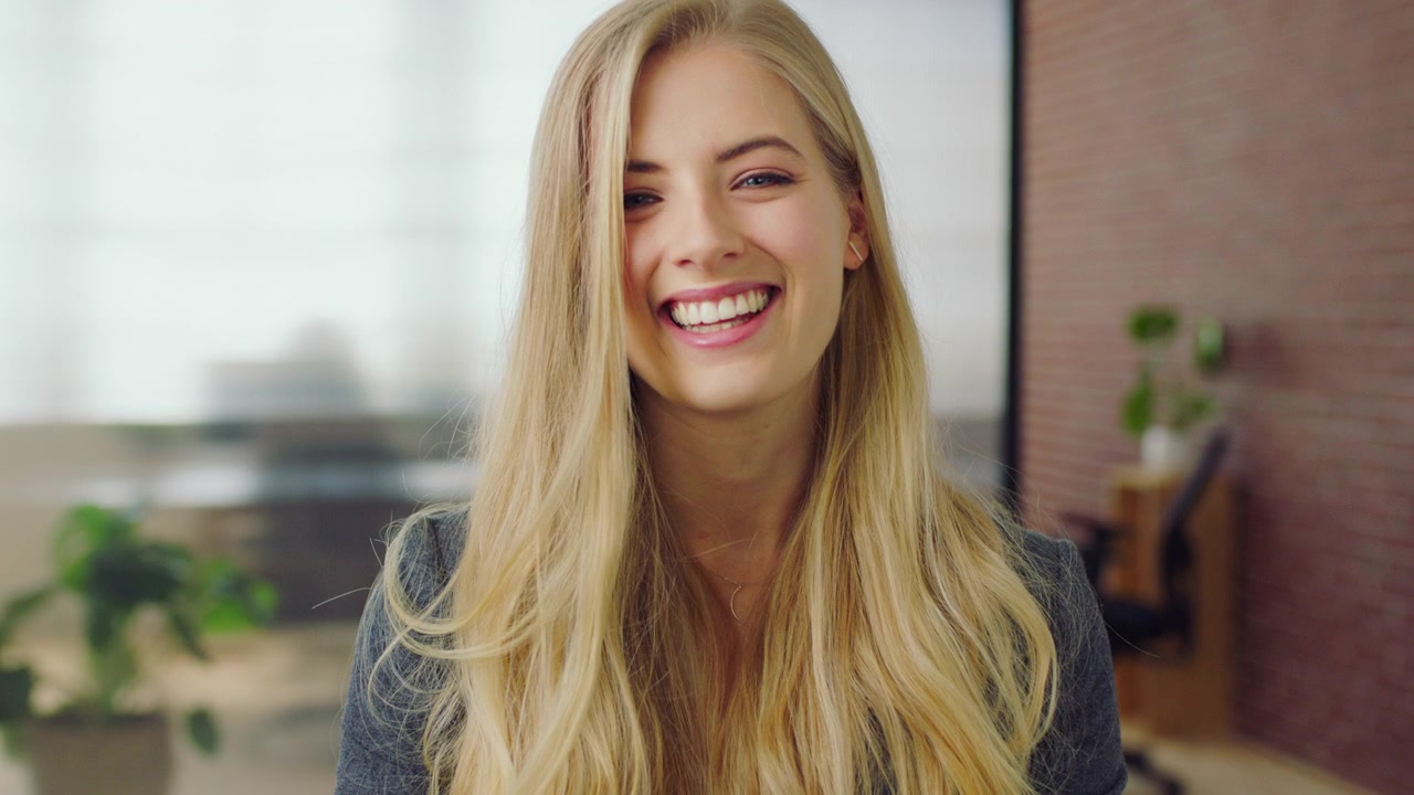 Young Blonde Woman Smiling and Laughing in Modern Office