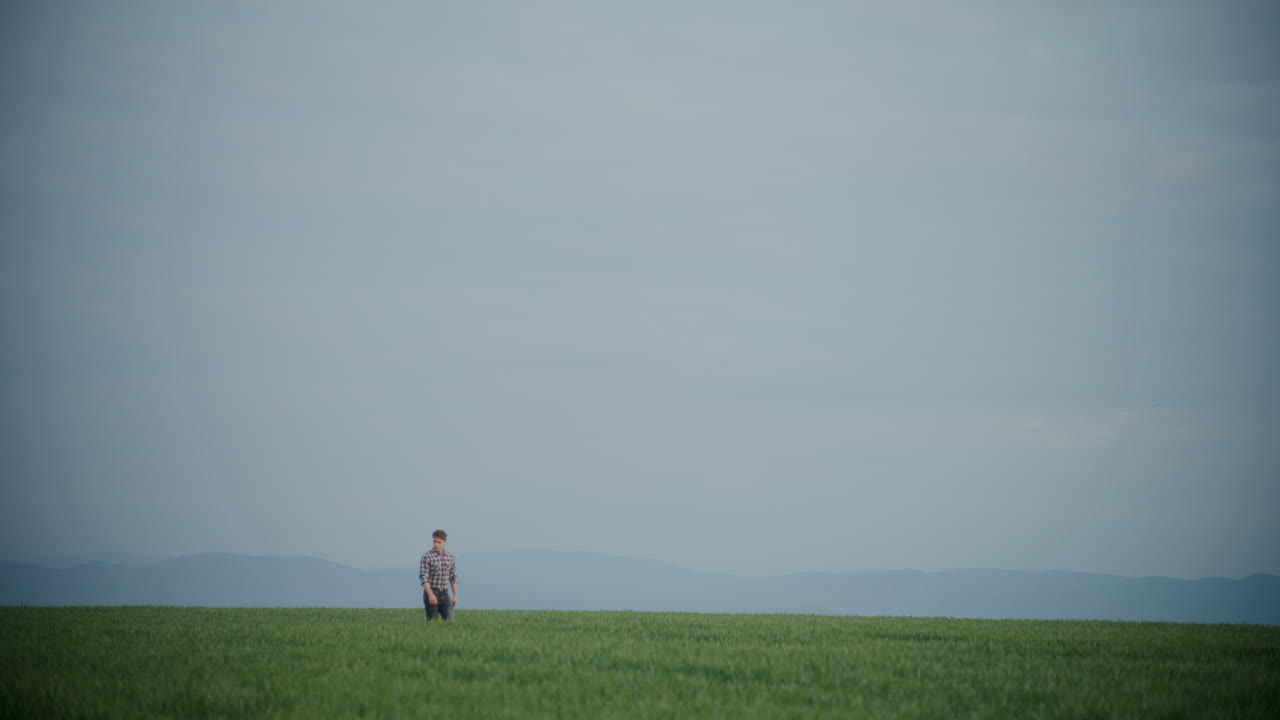 젊은 농부 가 하늘 에 맞서 들판 을 고 있다