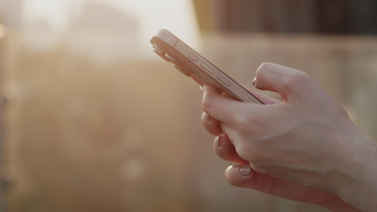 Primo piano delle mani che usano lo smartphone all'aperto al tramonto