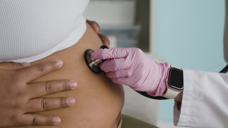 doctor examining pregnant woman with stethoscope