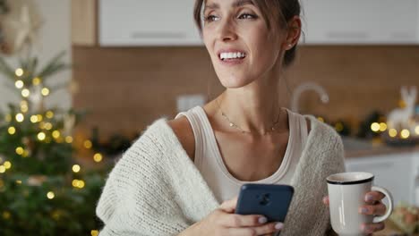 Caucasian-woman-with-cup-and-mobile-phone-in-Christmas-time.