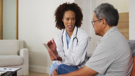 mixed race female doctor and senior man using tablet and talking