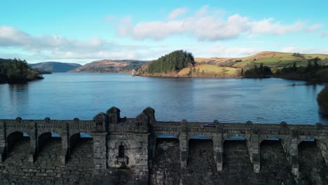 drone close in clockwise rotate of lake vyrnwy dam ramparts on a crisp sunny winter afternoon, cars crossing - wales, uk