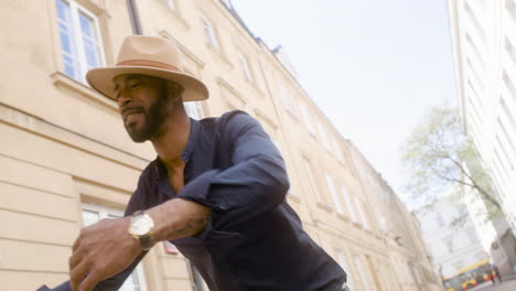 felice uomo afro-caraibico con cappello panama che balla ballo latino da solo nella strada della città vecchia 3