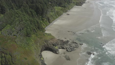 Slow-dropping-panning-drone-shot-of-rocky-cliffs-and-expansive-coastline