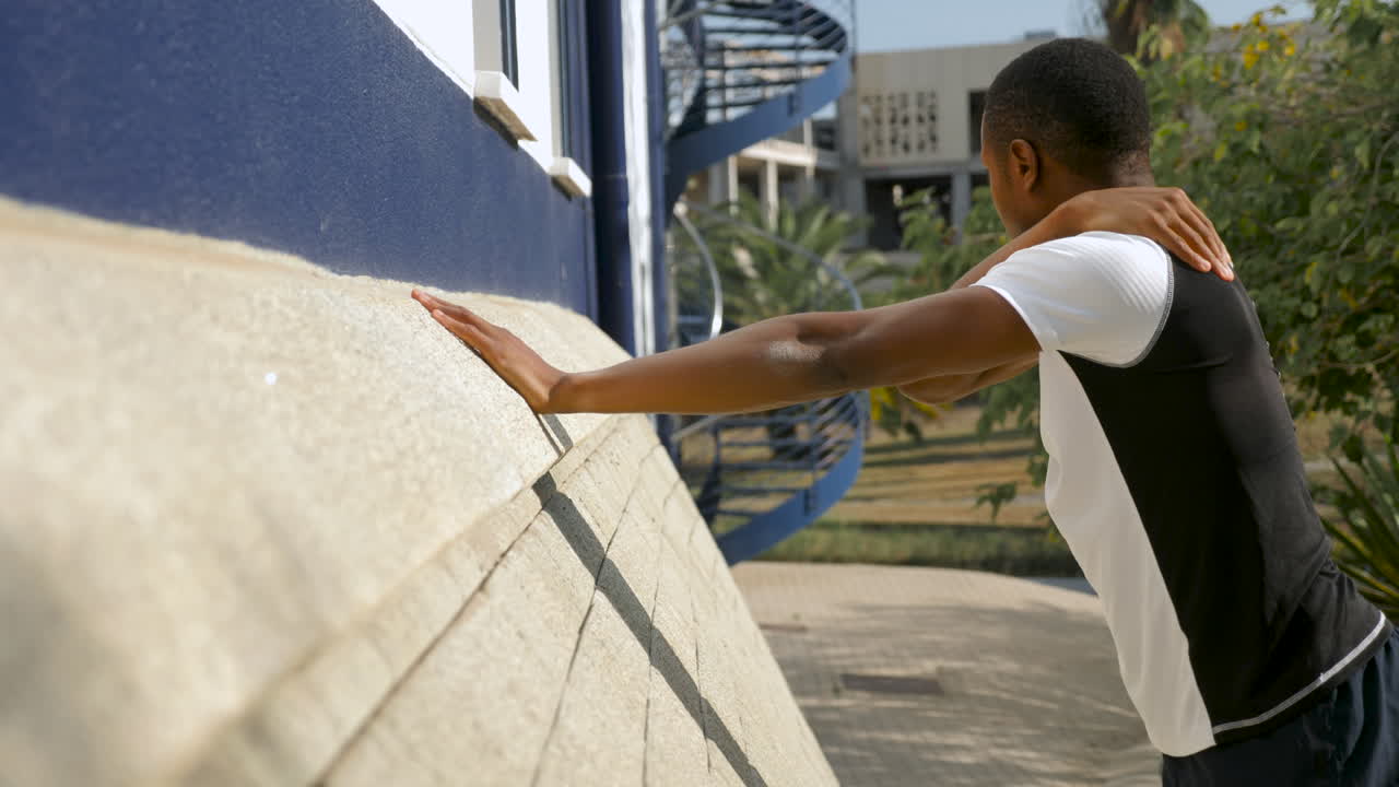 Young Black Man Stretching Arm And Shoulder Before Running Outdoors