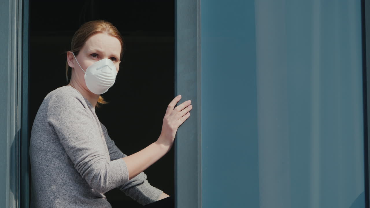 una mujer triste con una máscara se asoma por la ventana