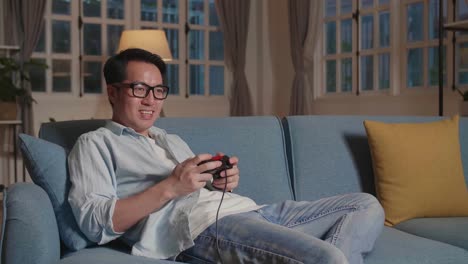 asian male gamer smiling while playing a game at home