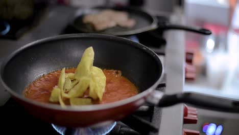 chef cook preparing a traditional mexican dish called chilaquiles mixing fried tortilla chips with hot tomato sauce in a pan at a local cafe diner restaurant in latin america