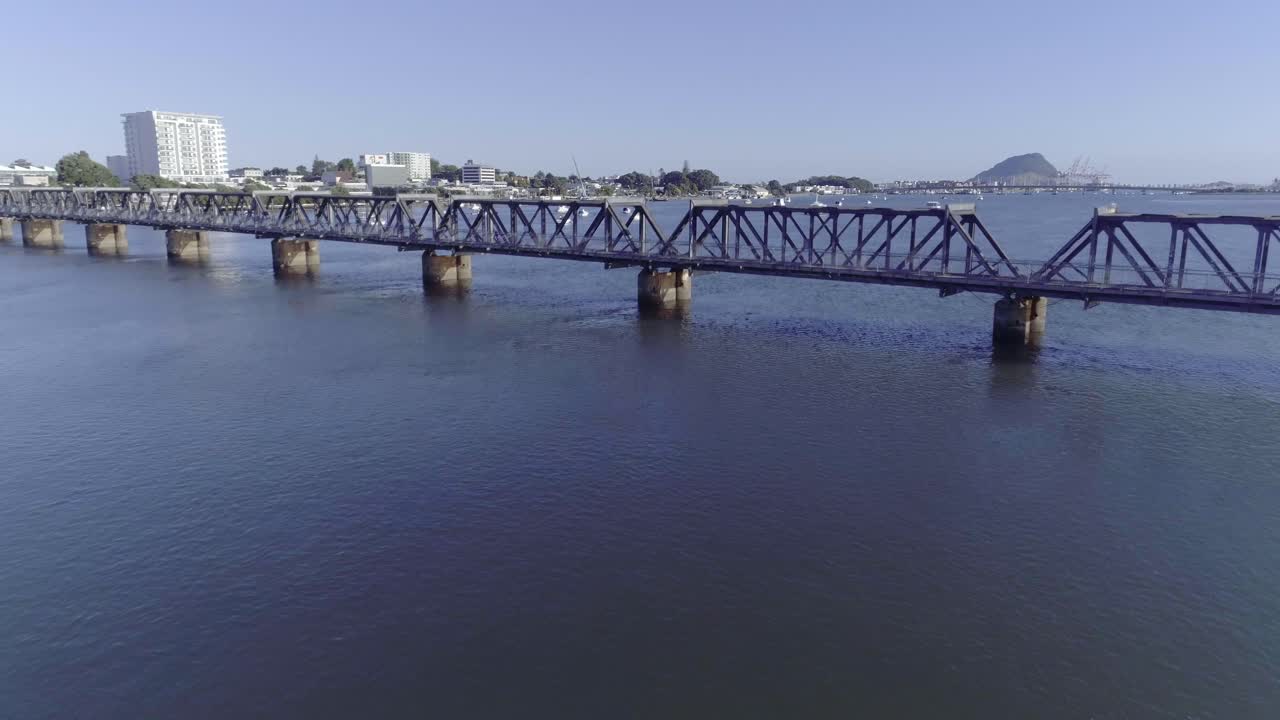 volando hacia el puente ferroviario matapihi con la ciudad de tauranga en el fondo, bahía de la abundancia, antena