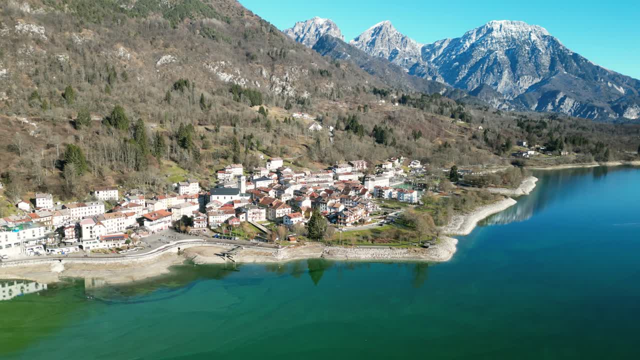 Ilmakuva Barcisin järvestä Italiassa: aurinkoinen talvipäivä, turkoosi vesi ja vuoret, joiden lumihuippuiset huiput näkyvät etäällä. Ihanteellinen matkailu-, luonto- ja maisemakuvapankkivideomateriaaliin.