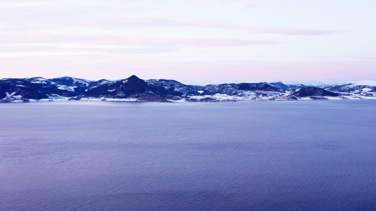 Fredfyldt vand i Norskehavet med bjerglandskab i det fjerne om vinteren.