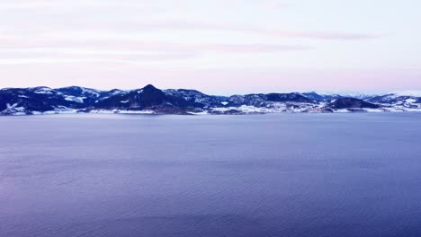 serene water of norwegian sea with mountain landscape in the distance at winter
