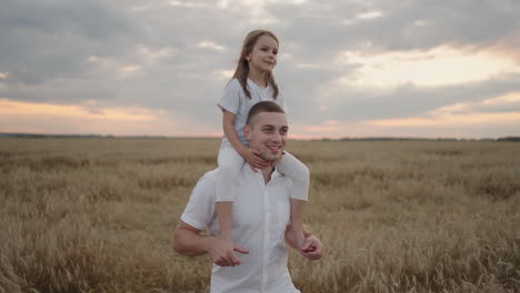 Glückliches-Kind-Und-Vater-Spielen-Im-Feld-Des-Reifenden-Weizens.-Kleine-Tochter-Auf-Den-Schultern-Des-Vaters.-Baby-Junge-Und-Papa-Reisen-Auf-Dem-Feld.-Kind-Und-Eltern-Spielen-In-Der-Natur.-Glückliches-Familien--Und-Kindheitskonzept