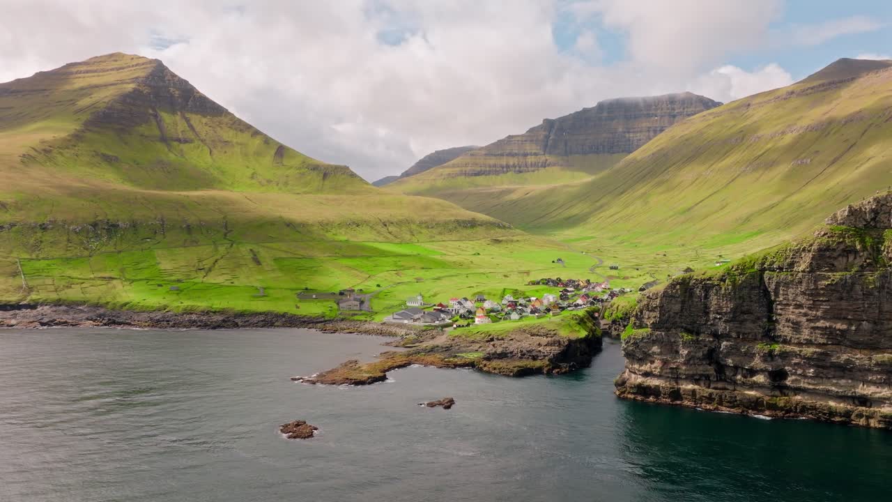 A peaceful village nestled among towering green mountains in Gjógv, Faroe Islands