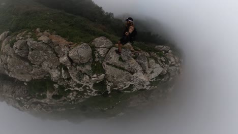 a young and fit solo hiker is jumping between rocks on the edge of the steep cliff of espigao amorelo in madeira, surrounded by mist, fog and clouds. a risky and dangerous act full of adrenaline.