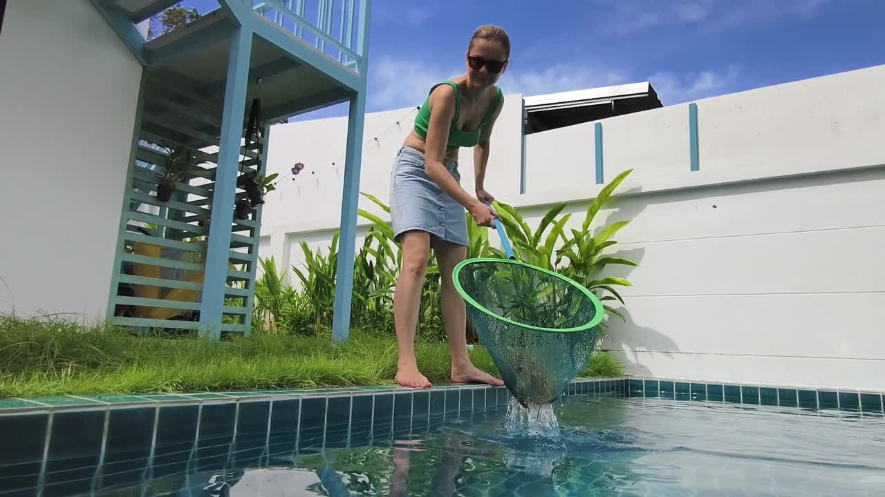 mujer limpiando la piscina con una red