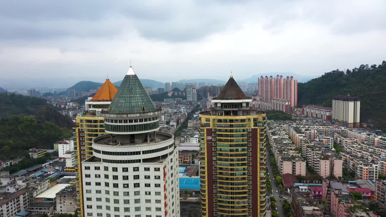 Aerial view over Guiyang, Guizhou Province, China, focusing on distinctive residential skyscrapers with colorful, pointed rooftops. The surrounding cityscape includes densely packed buildings.
