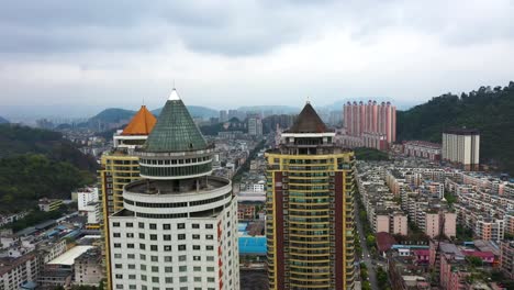 aerial view over guiyang, guizhou province, china, focusing on distinctive residential skyscrapers with colorful, pointed rooftops. the surrounding cityscape includes densely packed buildings.
